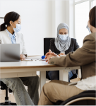 3 women sitting at table with medical masks on